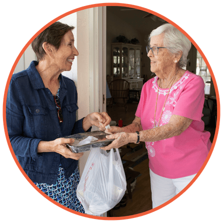 A Meals on Wheels volunteer delivering a meal to a senior.